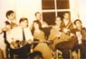 Στο καφενείο «Ο Μπάτης» του Χρήστου Βαλάκου στην προκυμαία Πλωμαρίου, στις αρχές της δεκαετίας του 1950. Διακρίνονται από αριστερά προς τα δεξιά  οι μουσικοί: Ζαγοραίος (μπουζούκι), Ζωή Ζαγοραίου (τραγούδι), Μιχάλης Βερβέρης ή «Τουρκογιάννης» (βιολί), Παντελής Σκυβαλάκης ή «Κρητικός» (ακορντεόν). Πίσω: Μανόλης Γιαγνίσης (ακορντεόν),  άγνωστος (κιθάρα), Ηλίας Ρουμελιώτης ή «Καραχάλιας»(κιθάρα).