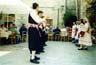 Μέλη του πολιτιστικού συλλόγου Μεστών Χίου, χορεύουν «Σούστα Νάξου» στο πλαίσιο του πανηγυριού των Ταξιαρχών, στην κεντρική πλατεία των Μεστών το 1999.