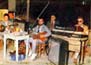 Στις Καρυές Χίου, το 1986. Διακρίνονται οι μουσικοί από αριστερά προς τα δεξιά: Γιάννης Φακίρης (μπουζούκι), Νίκος Ναδάλης (κιθάρα-τραγούδι), Γιάννης Μοράκης (αρμόνιο). Πίσω: Μάριος Νεαμονιτάκης (ντραμς).